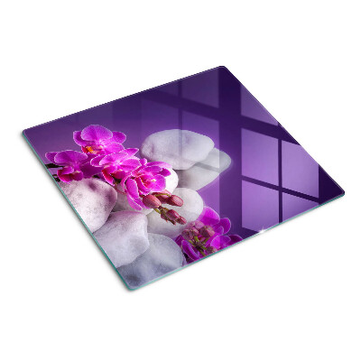 Krájecí prkénko skleněné Květy orchidejí na pozadí kamenů
