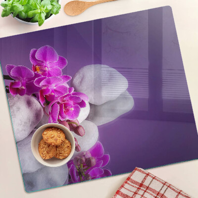 Krájecí prkénko skleněné Květy orchidejí na pozadí kamenů