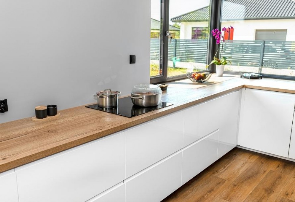 bílá kuchyň s dřevěnou pracovní deskou